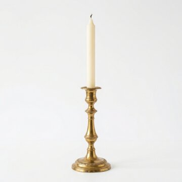 Antique brass candlestick with a single white candle isolated on white background