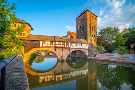 Scenic daytime view of the historic stone arch bridge spanning the calm waters of the Pegnitz River with beautiful architectural reflections in Nuremberg