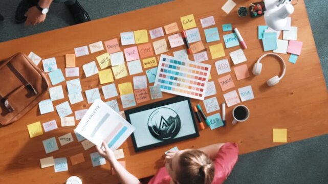Top view of skilled businessman hand choosing color palettes while designing logo graphic. Aerial view of smart interior designer design and select color theme by using color palettes. Symposium.