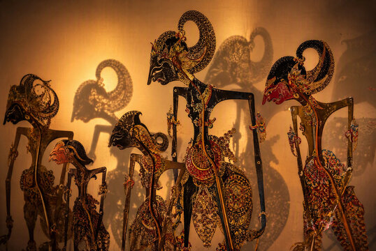 Traditional Javanese wayang kulit shadow puppets displayed with artistic backlighting and shadows.