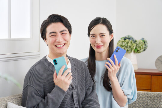 リビングでスマホを持っているカップルのポートレート　カメラ目線