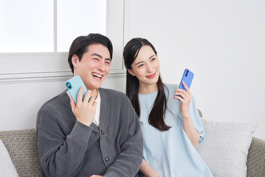 リビングでスマホを持っているカップルのポートレート　カメラ目線