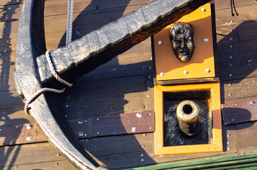 View of a gun port with stylized cannon, decorative sculpted face lid, and a large anchor attached to the wooden hull of a tourist galleon in Gdynia. © Wiesław Gajda