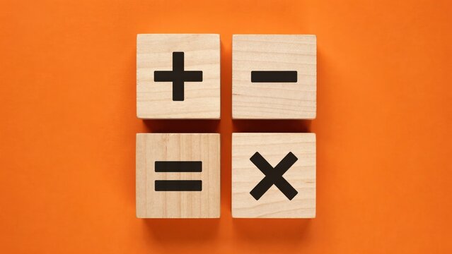 Wooden blocks with mathematical signs including plus, minus, equals, and multiply symbols arranged on an orange background. This photo is perfect for education, math, and accounting concepts.