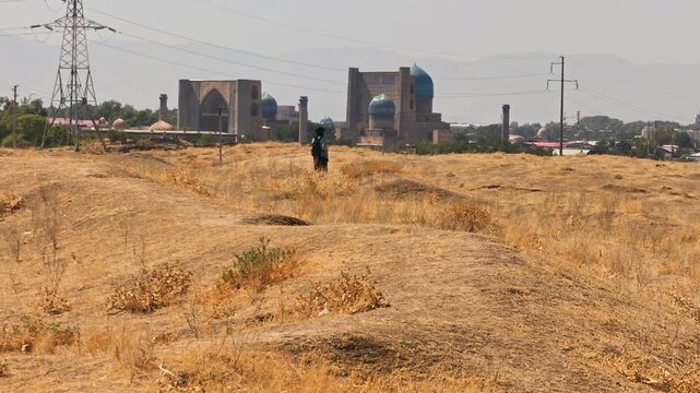 A woman in black looking at the Bibi Khanum mosque from the ruins of the Afrosiyab city