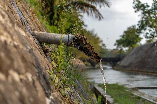 Close up view of clean water flowing from a broken drainage pipe into a river