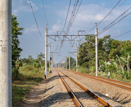Double track railway with overhead electric catenary poles extending into the distance