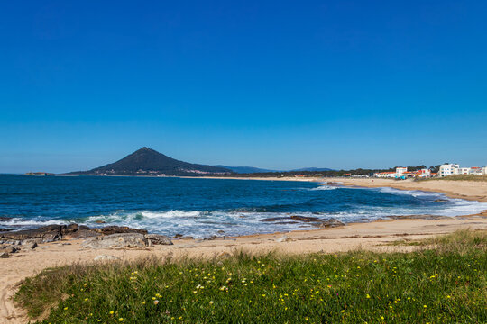 Scenic view of a sandy shoreline of the Atlantic Ocean with Mount Santa Tecla on the horizon along the Camino de Santiago route in Portugal