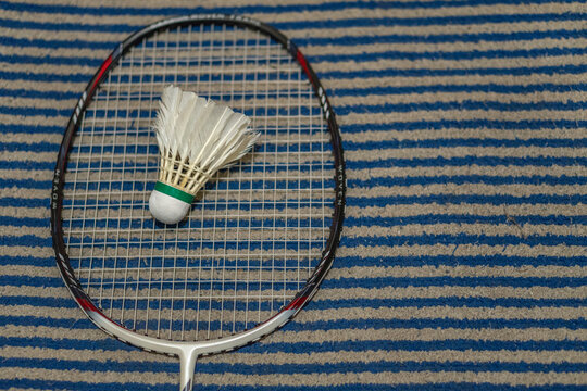 Badminton racket and shuttlecock on striped carpet mat surface