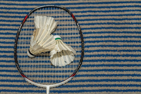 Badminton racket and shuttlecock on striped carpet mat surface