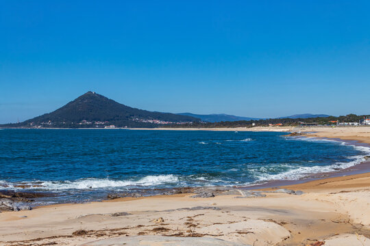 Scenic view of a sandy shoreline of the Atlantic Ocean with Mount Santa Tecla on the horizon along the Camino de Santiago route in Portugal