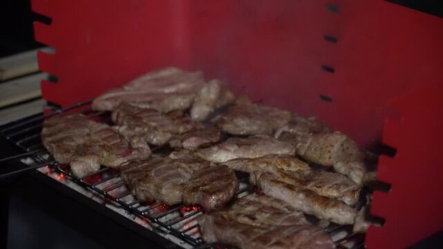 red charcoal barbecue grill sits in a warm and inviting outdoor patio, with grilling essentials nearby, including a gas torch, lighter fluid, and a stack of charcoal briquettes prepared for use