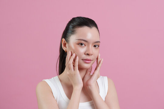 Asian woman framing face with hands for beauty and skincare concept
