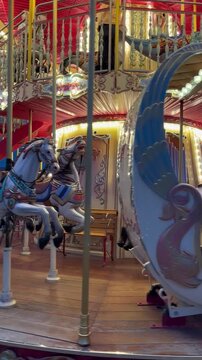 A colorful carousel with a blue horse and a fish design. The background features bright lights and ornate decorations, creating a festive atmosphere.
