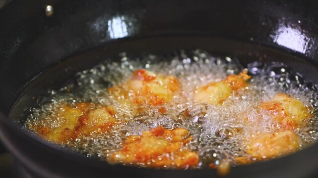 中華鍋の中で油で揚がる美味しそうな唐揚げのクローズアップ（シズル感・調理動画）