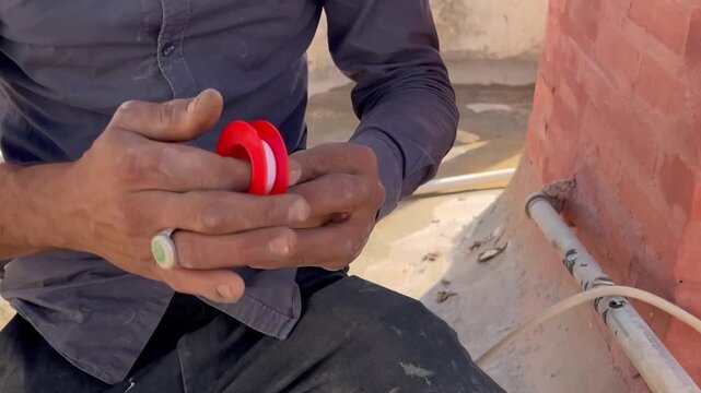 Plumber Applying Teflon Tape to a Pipe Fitting
