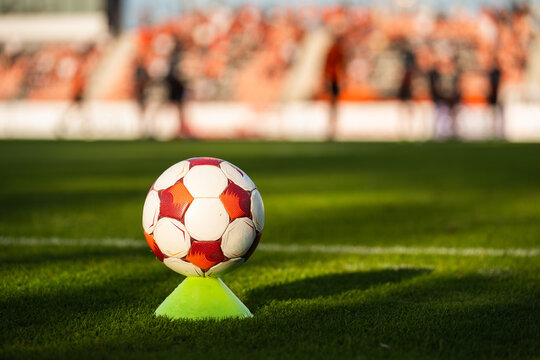 Soccer ball on a training cone near the touchline during a football match with players and stadium blurred in background