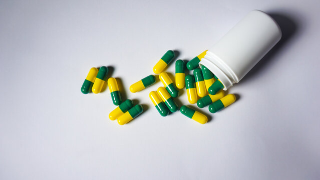 Several green yellow capsules spilled from bottle. Top view angle. 