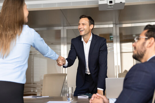 Businesswoman shaking hands with male client or partner as successful business deal, starting professional collaboration in corporate office meeting room. Agreement, human resources, relationships