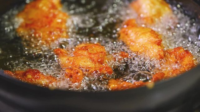 中華鍋の中で油で揚がる美味しそうな唐揚げのクローズアップ（シズル感・調理動画）