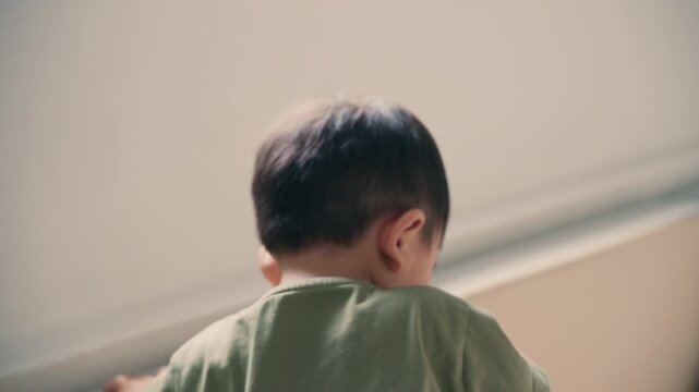Rear view of little Asian boy looking away indoors, 4K resolution