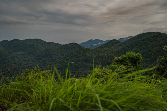 Panoramic mountain range landscape view with green grass in foreground near Pandavan Para Urukunnu.