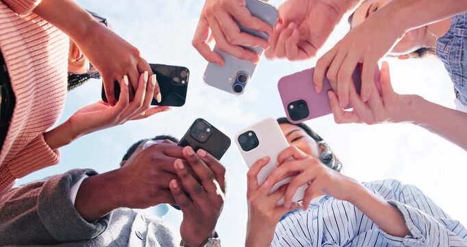 Below, hands and friends with phone in circle for networking, online connection or share contact. Outdoor, group and people with mobile addiction for communication, data sync or social media app