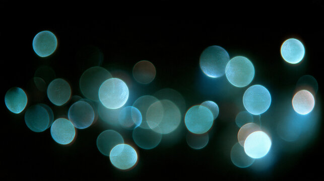 Abstract teal cyan bokeh lights on dark black background, blurred glowing circles with soft focus, defocused aqua light orbs, dreamy night shimmer effect, sparkling bokeh texture for party design
