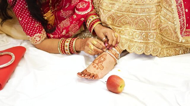 Indian bride wearing traditional jewelry and henna applying anklet in Delhi