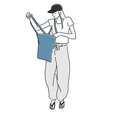Stylish young woman wearing cropped mini T-shirt and relaxed sweatpants with baseball cap, colorful tote bag and flip flop sandals