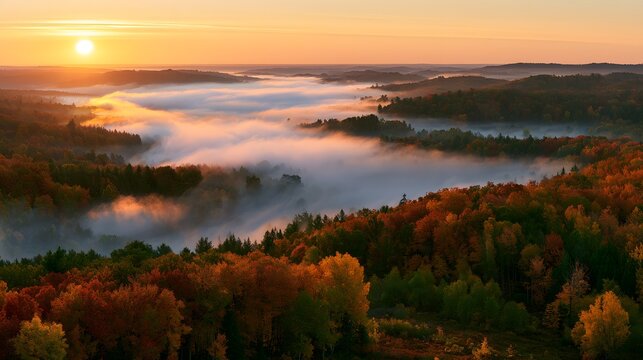Sunrise over a misty autumn valley filled with fog, rolling hills, and vibrant colored forests