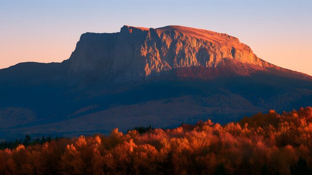 Stunning sunrise lighting up the massive stone face of mount katahdin during peak fall foliage