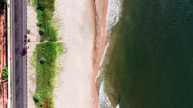 Footage shows Xuan Thuy in Mui Ne, Lam Dong during morning and evening. Waves hit the shore while cars drive along the road. Grass grows by the water in this lively area.