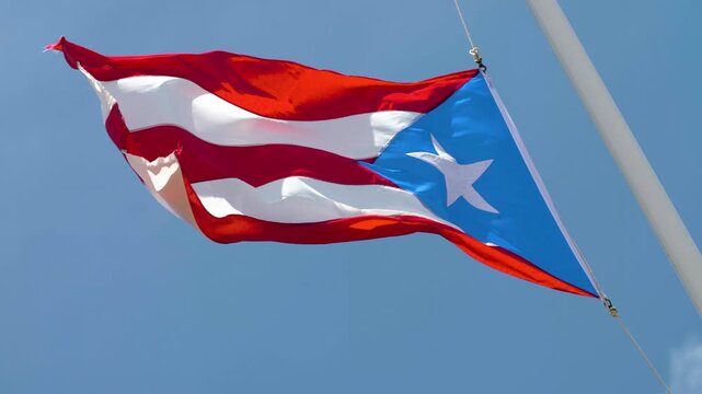 The Puerto Rican flag waving during strong wind at normal speed on a sunny day. Flag waves energetically due to windy clear sky weather,