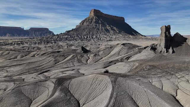 Drone Shot of ATV Vehicle Moving in Desert Landscape Under Rock Formation and Factory Butte, Utah USA