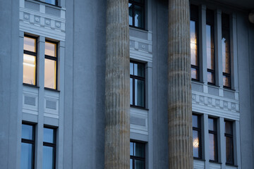 Classical building exterior with monumental columns and ornamented window surrounds, showing facade construction elements for architectural design and property documentation © K