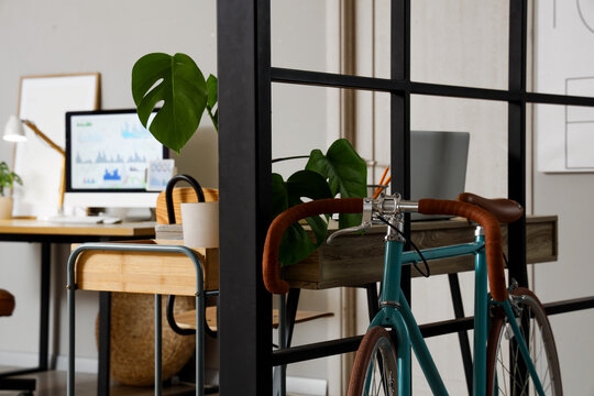 Remote work and modern office lifestyle, bicycle parked in a contemporary home workspace with a computer desk and indoor plants for creative professionals