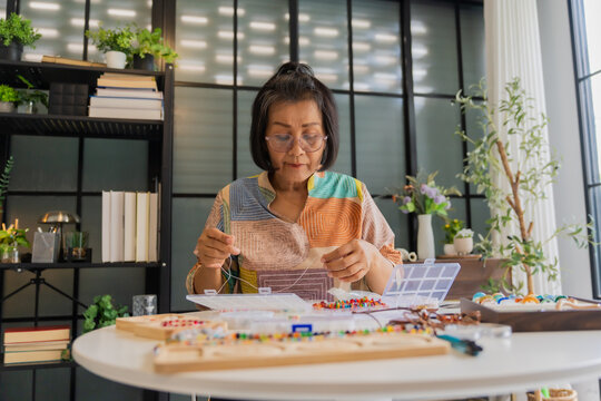 Mature Asian woman making necklace handcrafted