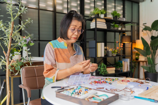 Mature Asian woman making necklace handcrafted