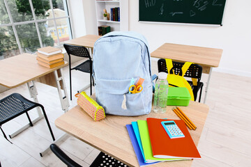 Back to school education concept, student backpack with supplies and stationery on a classroom desk for academic learning and student preparation © Pixel-Shot