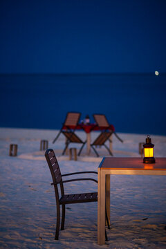 Two chairs and a table in a white sand beach at night for a romantic scene dinner restaurant in Maldives