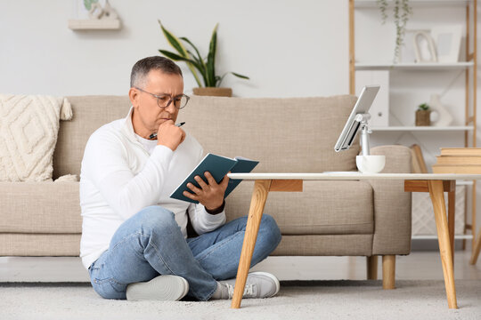 Lifelong learning and personal development, mature man studying with notebook and tablet at home for professional growth and continuing education