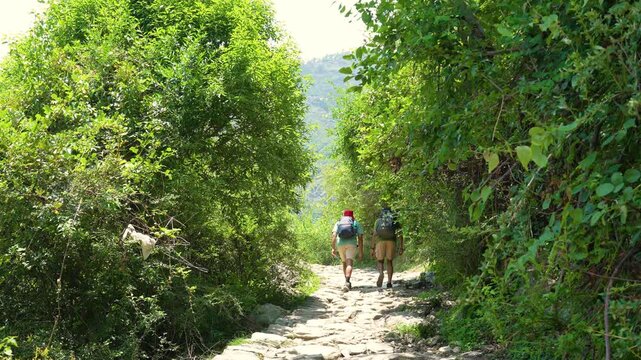 Two hikers trekking on a stone path towards Rudranath Temple in Gopeshwar Chamoli Uttarakhand India