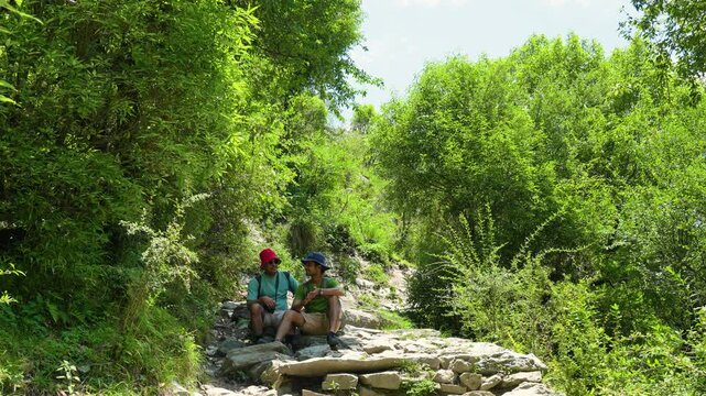 Two hikers resting on a stone path during a trek near Rudranath Temple in Gopeshwar Uttarakhand