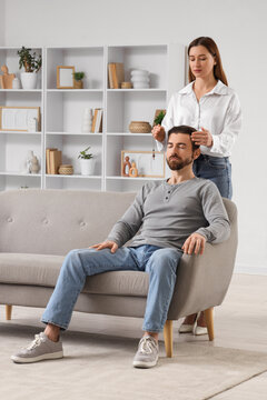 Female psychologist with pendulum hypnotizing young man in office