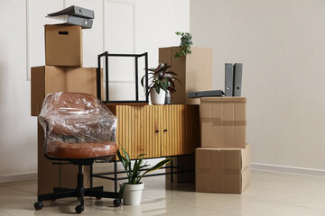 Plakat Cardboard boxes with chest of drawers and chair in rented office on moving day