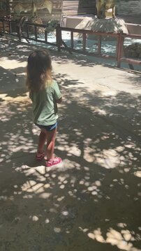 Little girl looking at pterosaur figure in dinosaur park on sunny day. High quality 4k footage