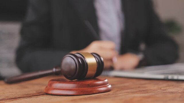 Justice and law concept. Gavel on sounding block in hand's Male judge at a courtroom, working with document law books, report the case on table in modern office.