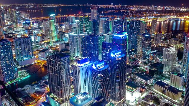 Miami downtown night hyperlapse with dynamic drone 360 orbit flight around brickell financial district, fast cityscape time-lapse of Florida luxury real estate and illuminated skyscrapers panorama