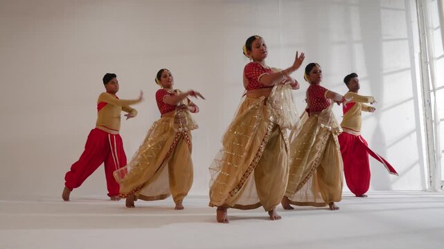 A group of dancers is performing a traditional Indian dance indoors
